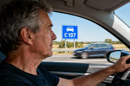 Conducteur de 55 ans regardant un panneau bleu de route pour automobile sur une autoroute française