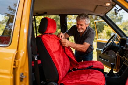 Homme de 55 ans en train d'installer un couvre-siège automobile rouge vibrant dans l'habitacle d'une voiture