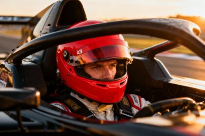 Pilote de course européen portant un casque rouge vif dans le cockpit d'une voiture de course