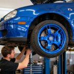 Volkswagen Golf 4 modifiée avec kit carrosserie R32 et jantes custom dans un atelier, mécanicien ajustant la suspension
