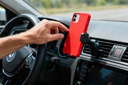 Support téléphone voiture moderne avec coque rouge vibrante sur un dashboard, main conducteur ajustant le dispositif